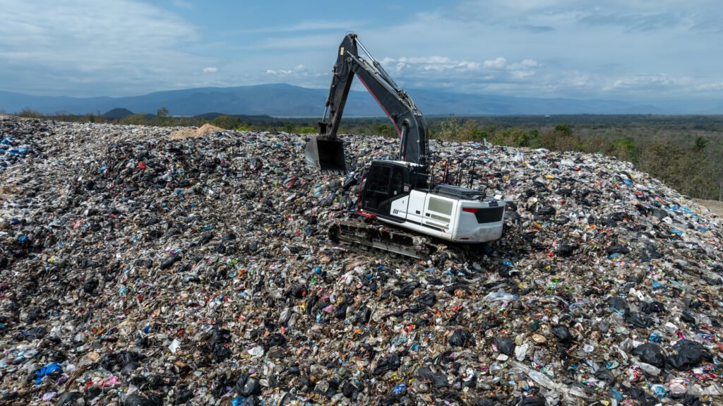 Garbage dump pile in trash dump or landfill, Landfill with waste disposal, Garbage truck unloads rubbish in landfill, Truck waste dump waste from household, Excavator work garbage waste, Aerial view.